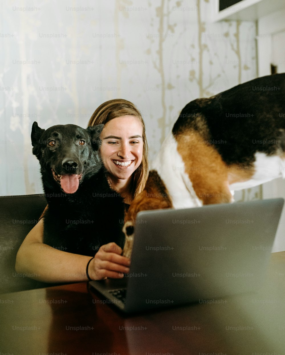a woman sitting at a table with a dog and a laptop