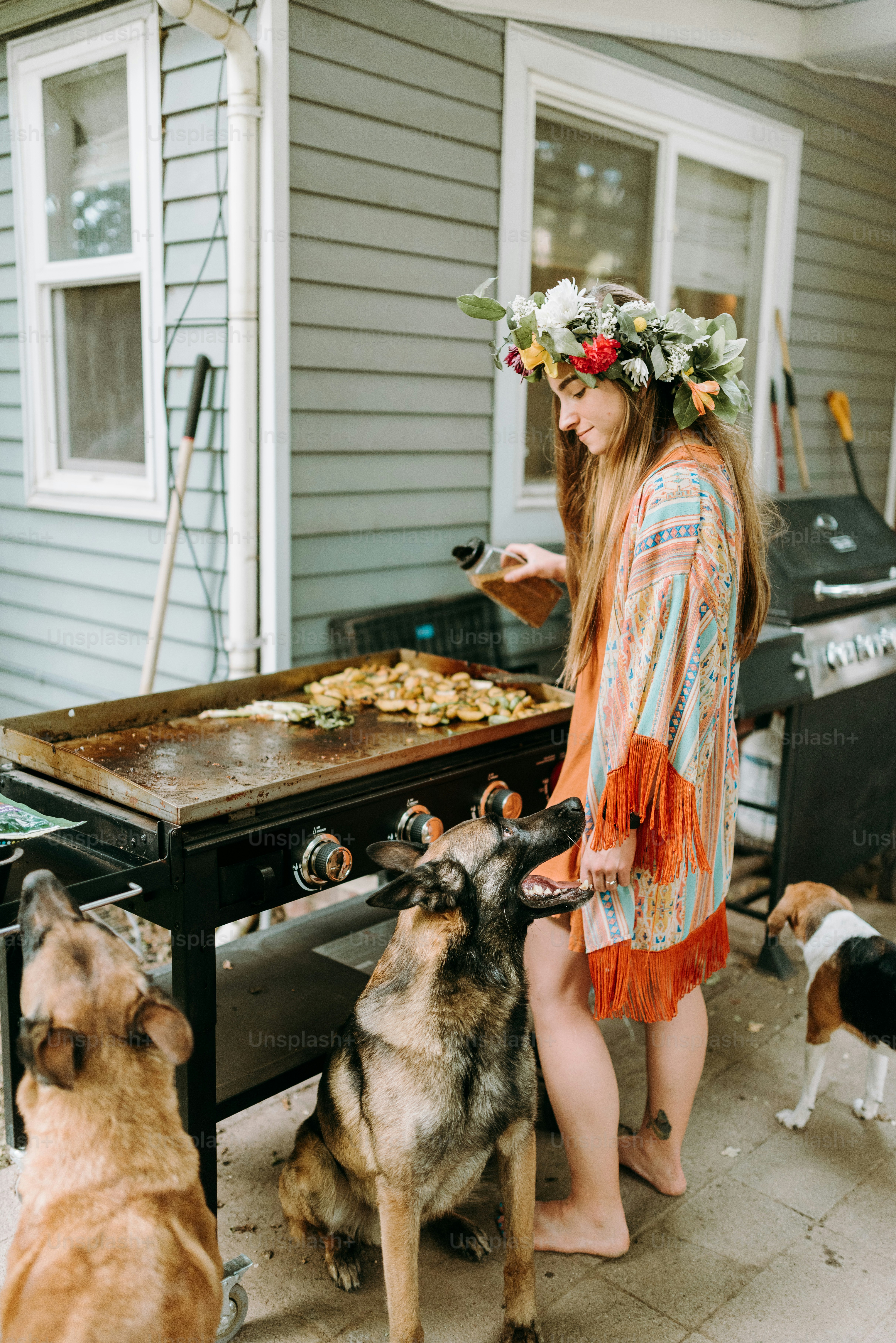 a woman standing next to a dog near a grill