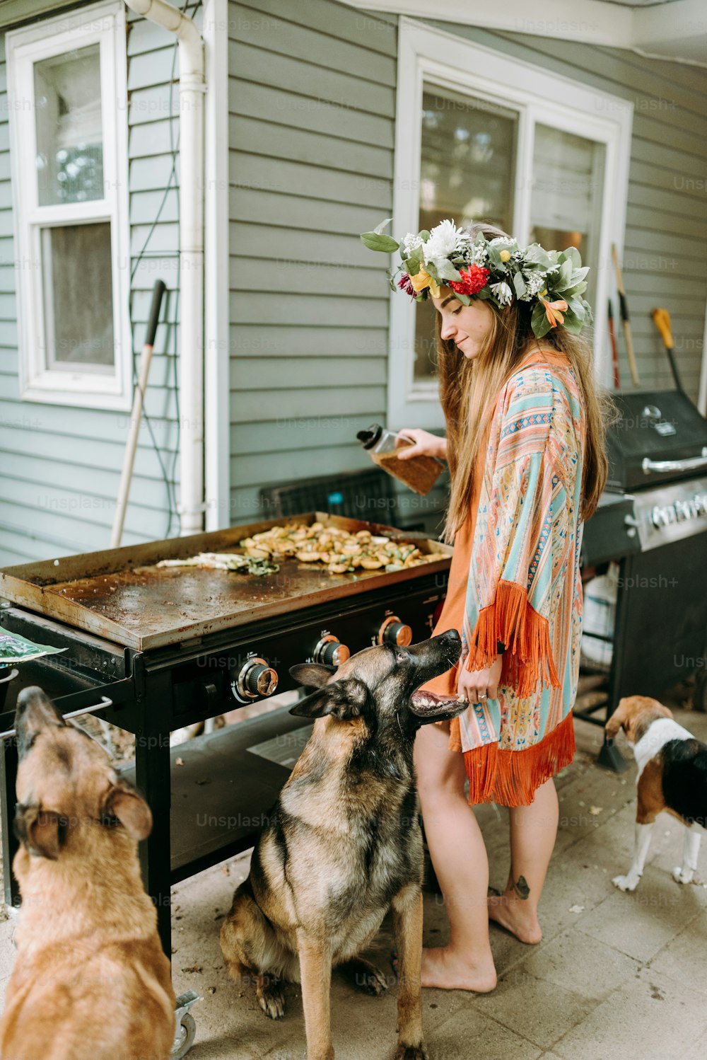 a woman standing next to a dog near a grill