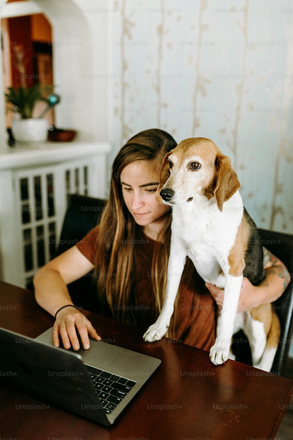 uma mulher sentada em uma mesa com um cachorro no colo