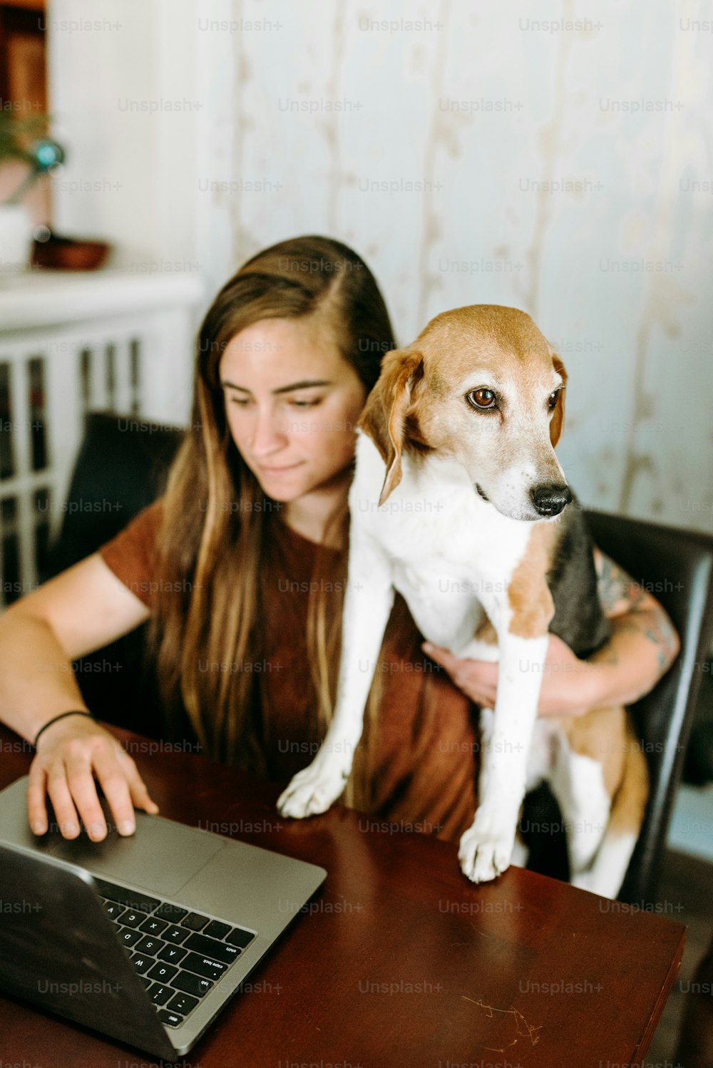 uma mulher sentada em uma mesa com um cachorro no colo