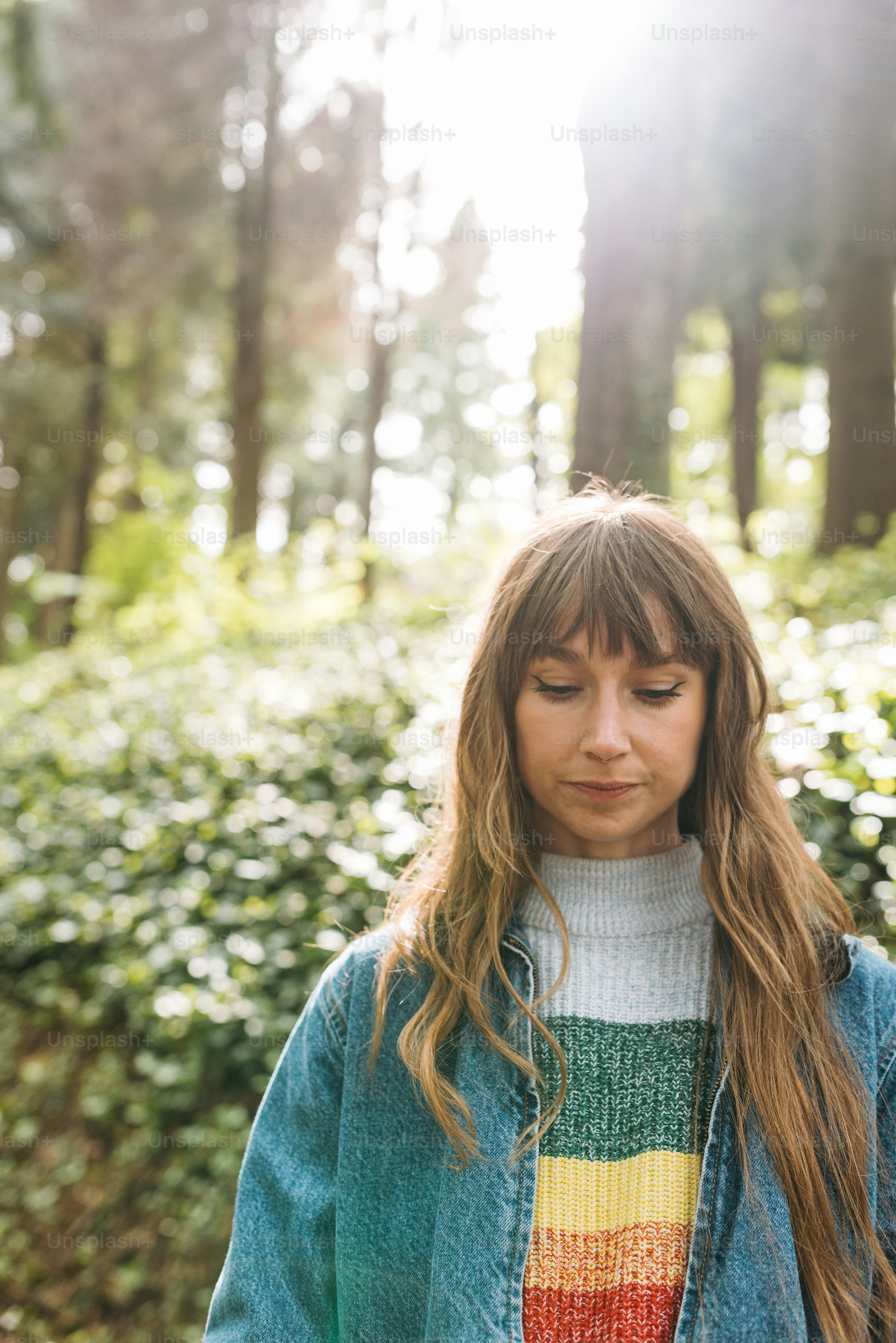 a woman with long hair standing in a forest