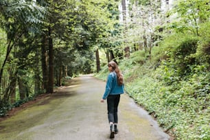 a woman walking down a road in the woods
