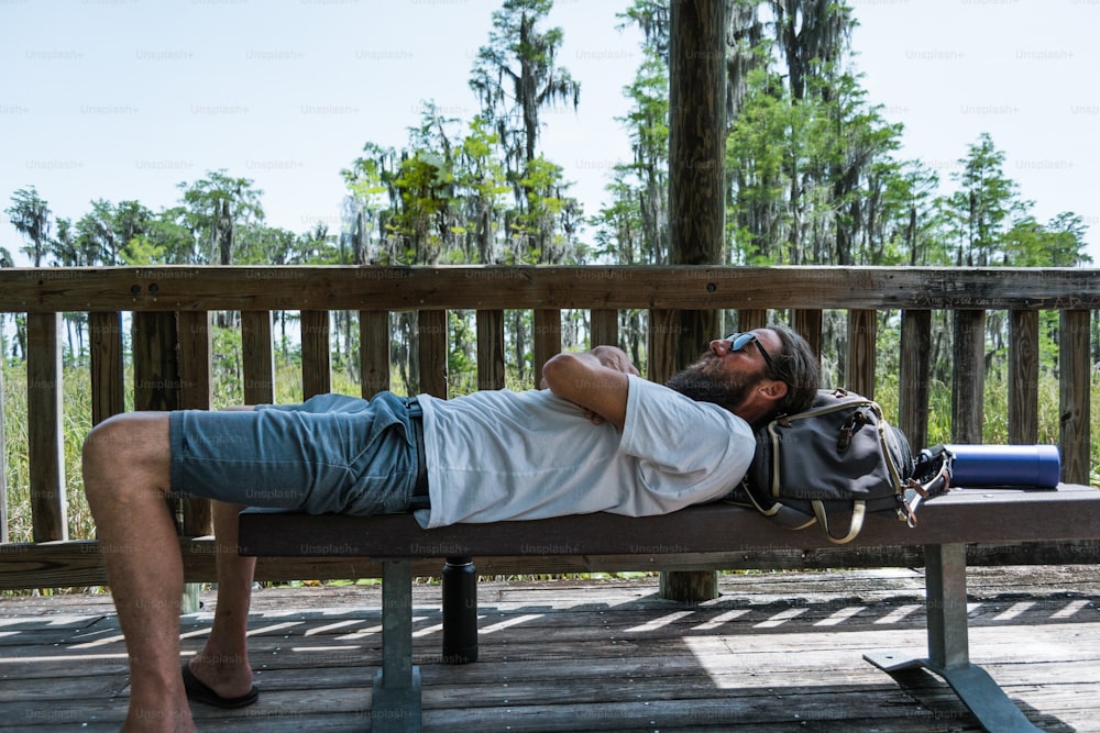 a man laying on a bench with a hand bag