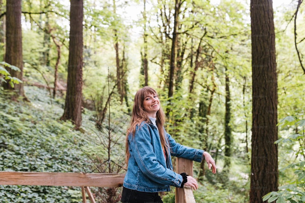 a woman standing on a wooden bridge in the woods