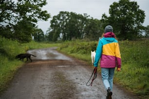 a woman walking down a dirt road with a dog