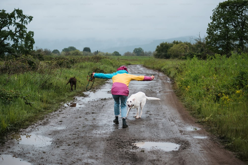 a woman walking a dog down a muddy road