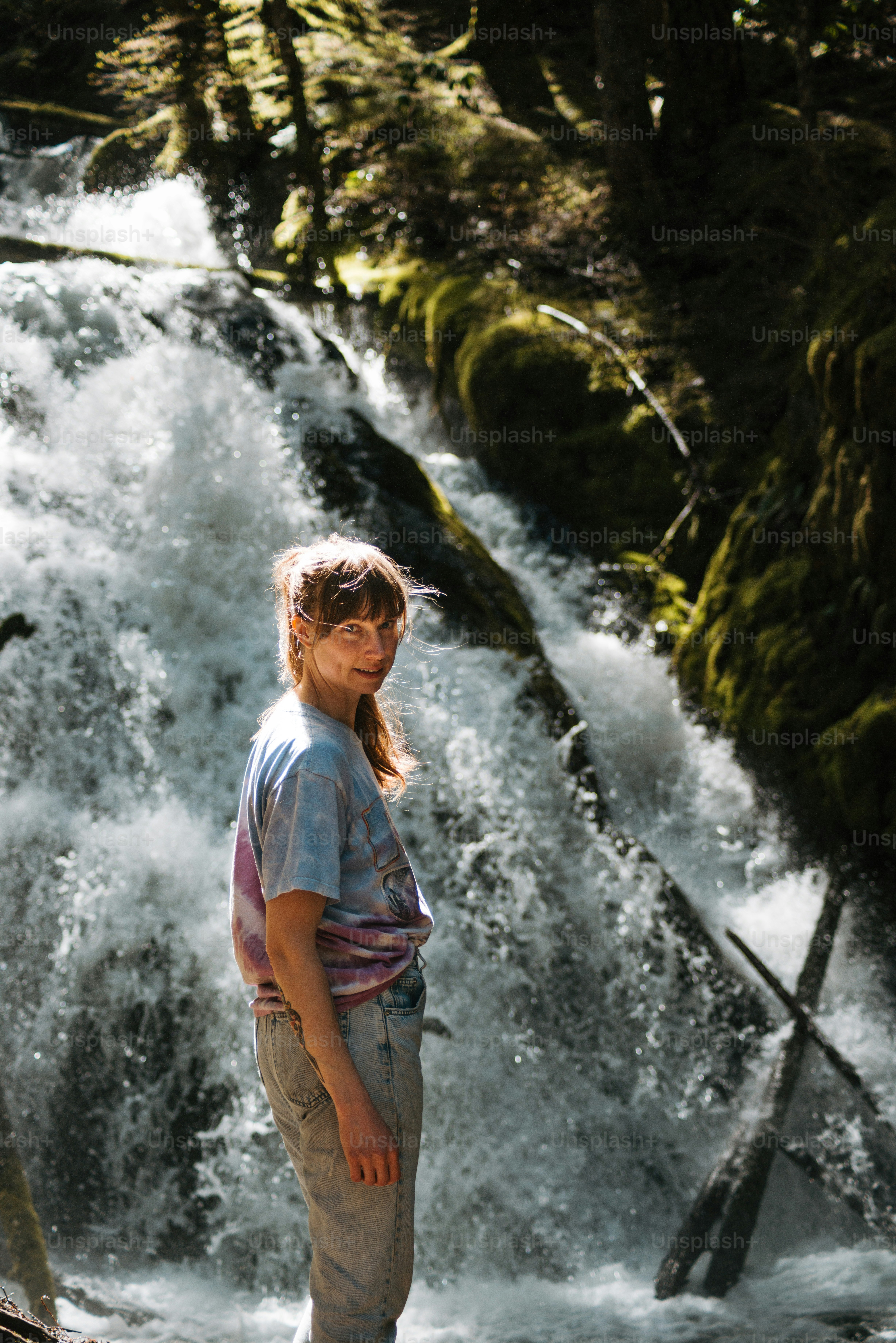 A young girl standing in front of a waterfall photo – People in nature ...