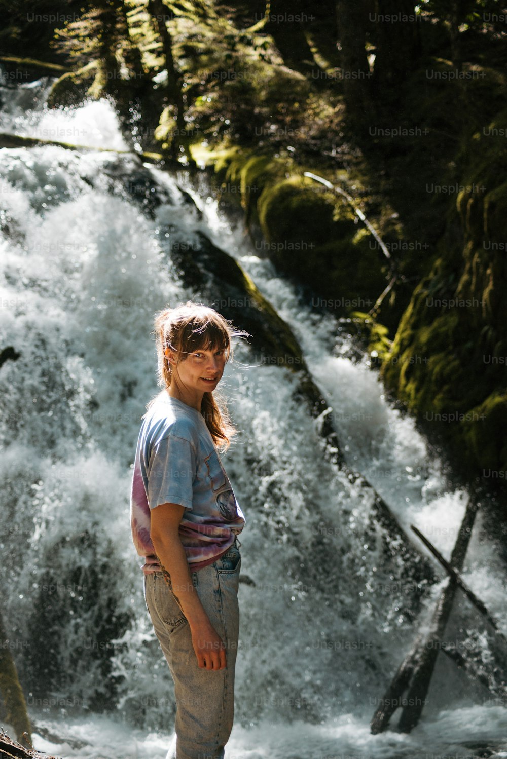 a young girl standing in front of a waterfall