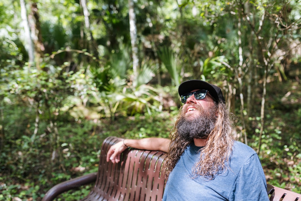 a man with long hair and a beard sitting on a bench