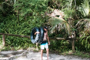 a man carrying an inflatable tube on a beach