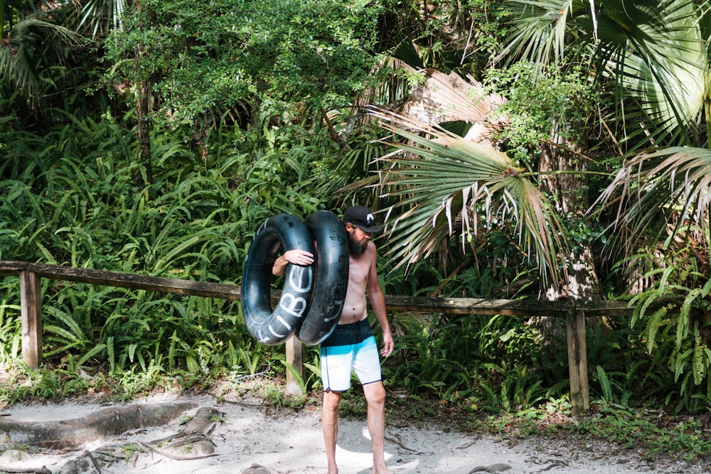 Un hombre cargando un tubo inflable en una playa