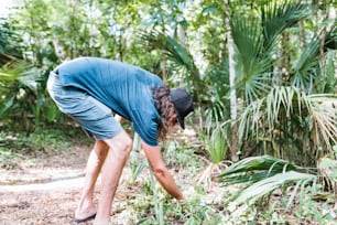 a man bending over to pick up a plant