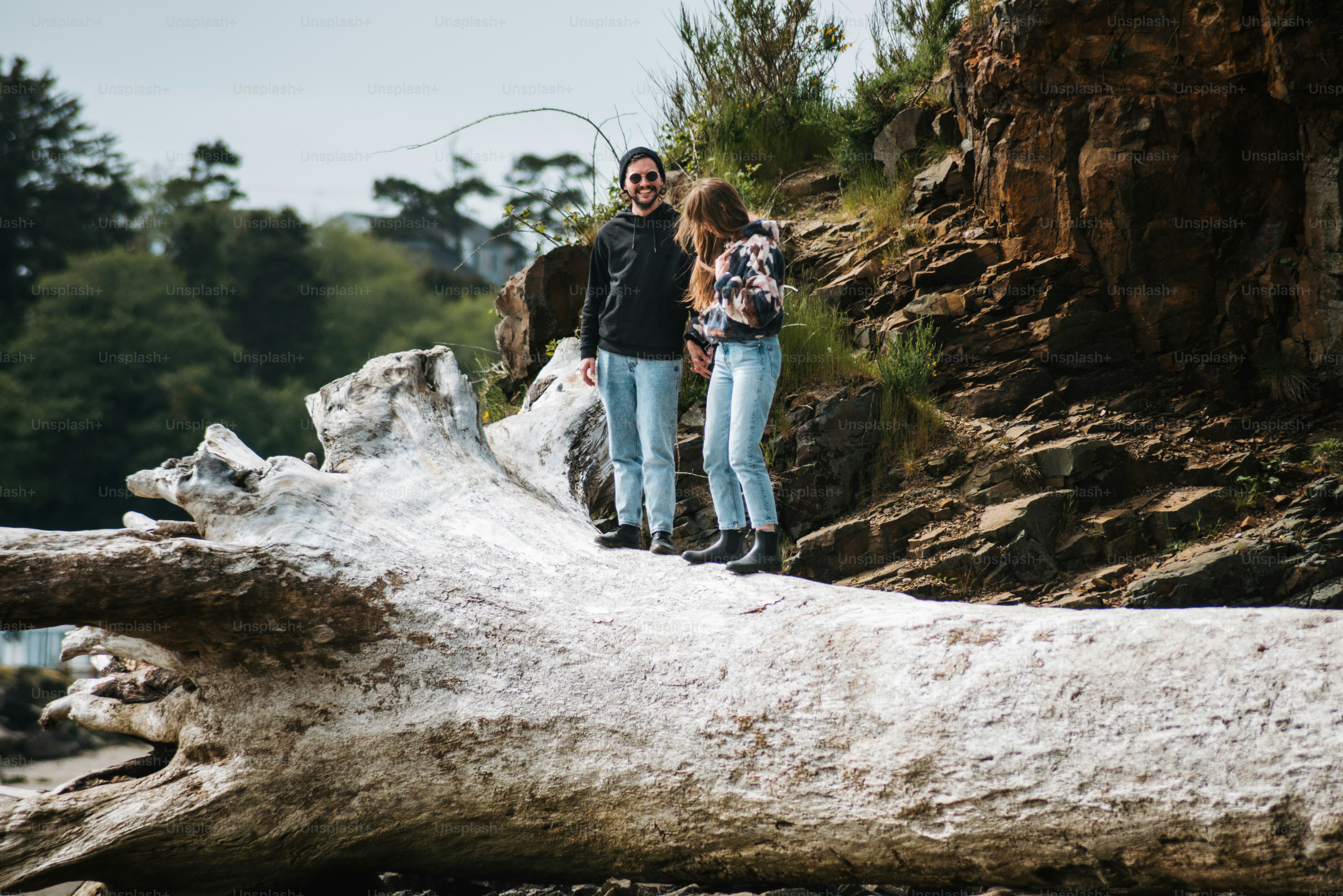 a man and a woman standing on a fallen tree