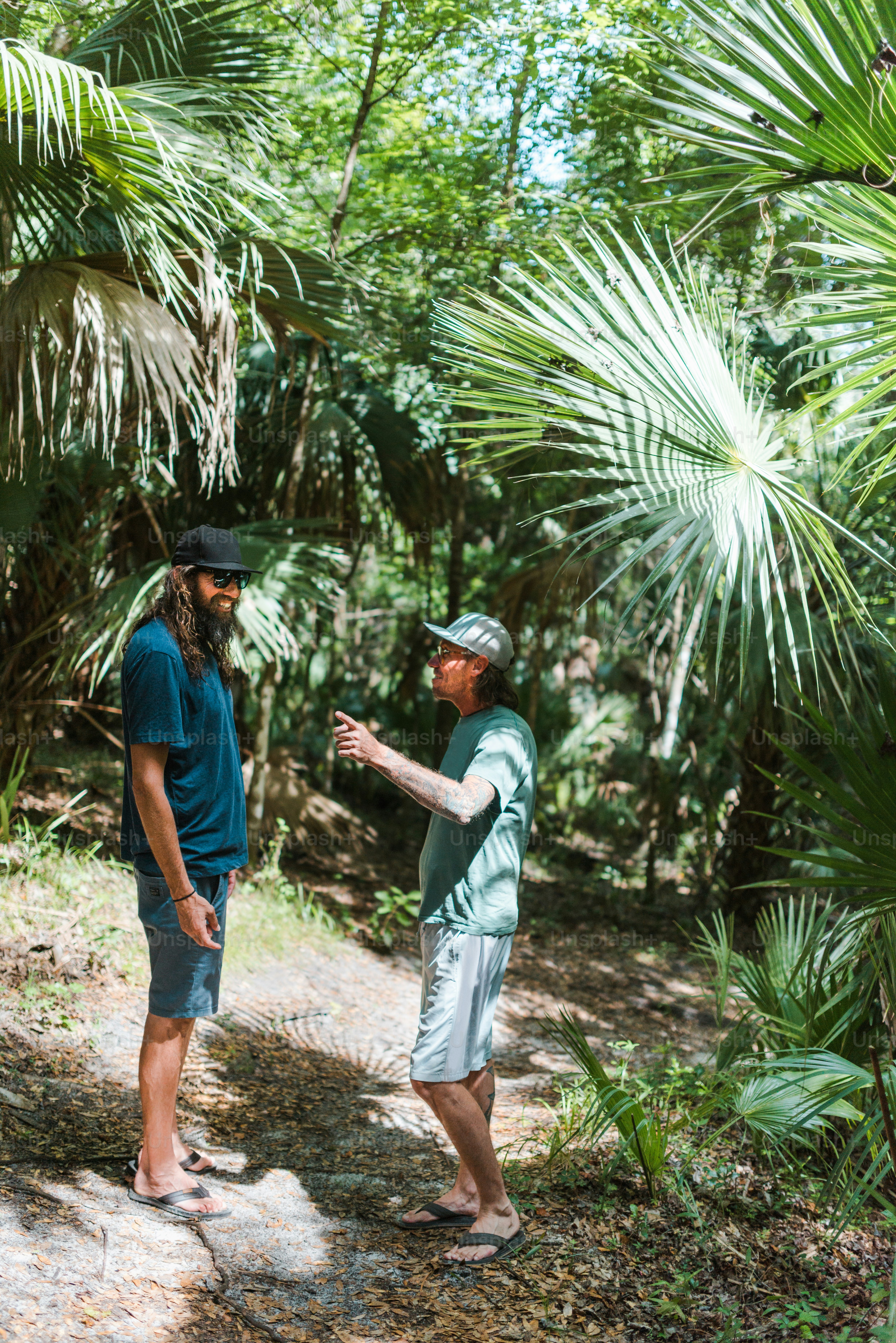 a couple of men standing next to each other in a forest