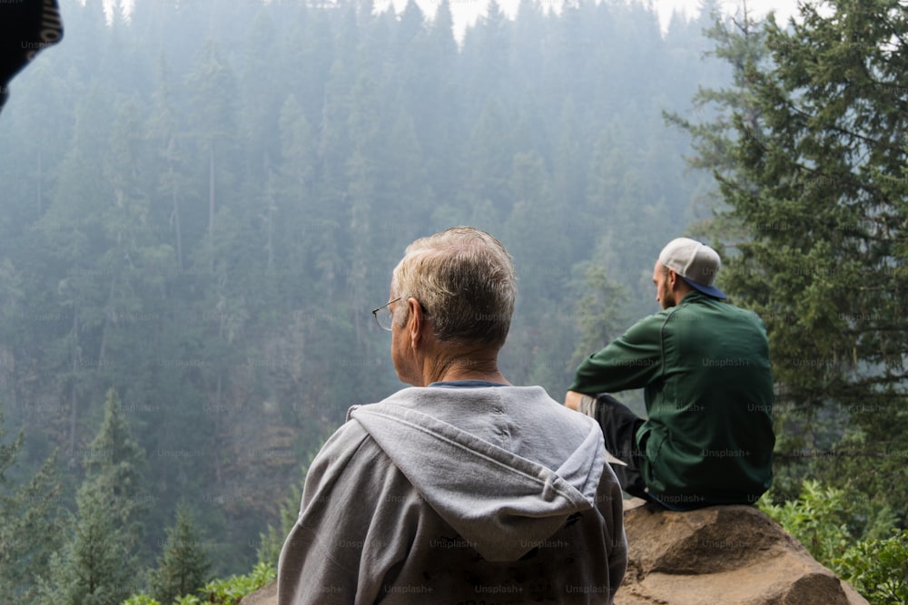 a couple of men sitting on top of a mountain