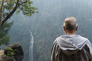 a man standing in front of a waterfall