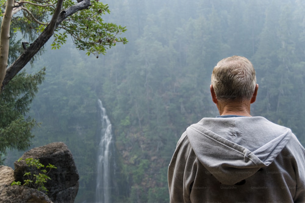 Un uomo in piedi davanti a una cascata
