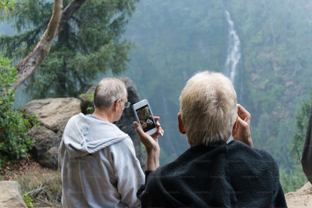 a man and a woman taking a picture of a waterfall