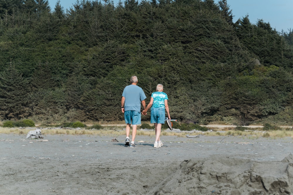 um homem e uma mulher de mãos dadas enquanto estão em pé em uma praia