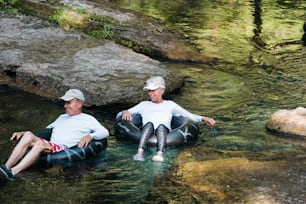 a couple of men sitting on inflatables in a river