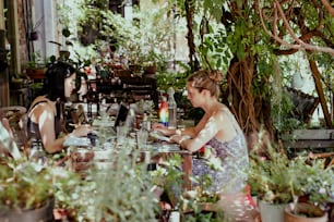 화분 앞 테이블에 앉아 있는 두 명의 여성