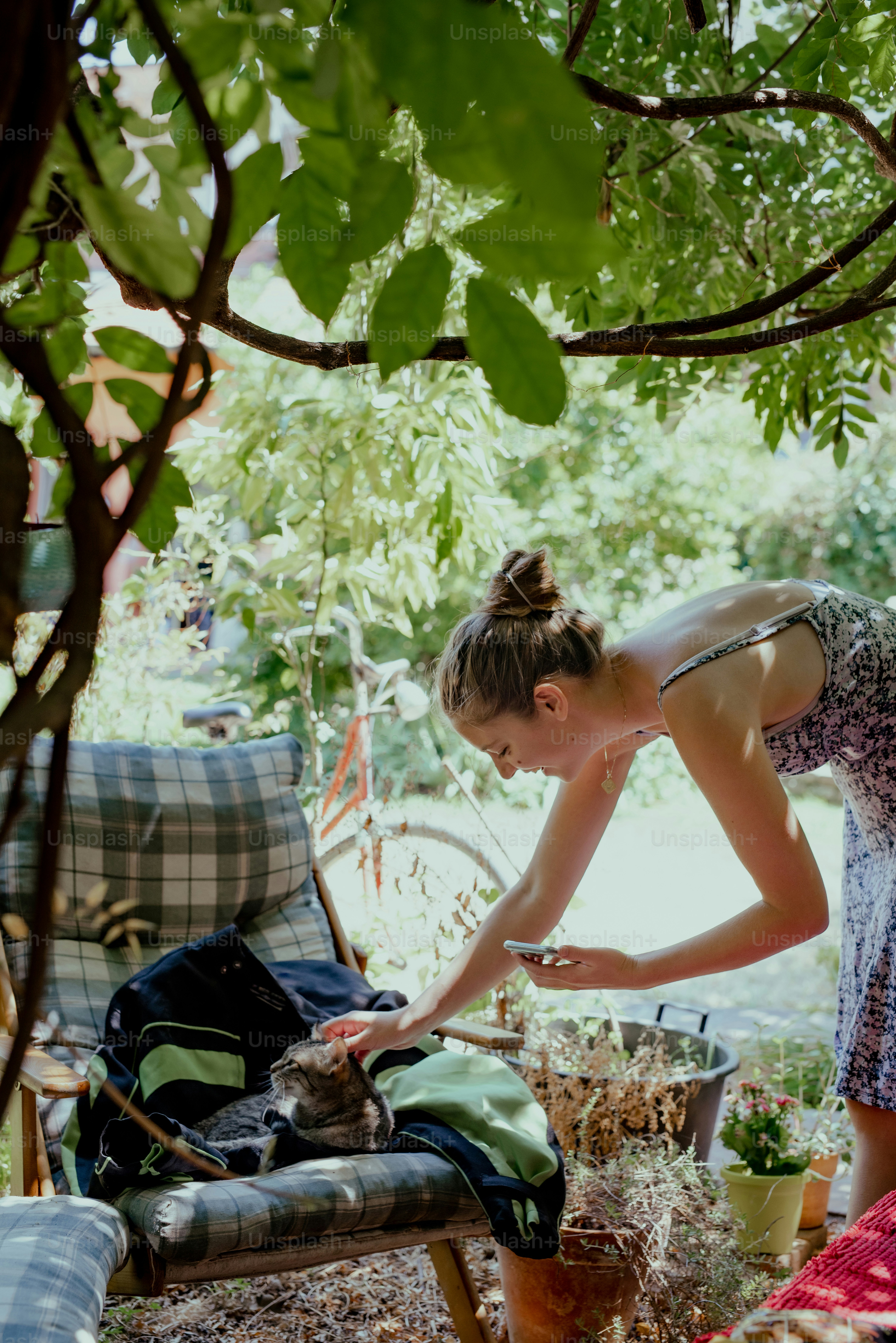 a woman is bending over to pet a cat