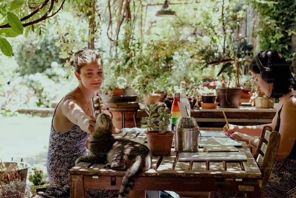 a couple of women sitting at a table with a cat