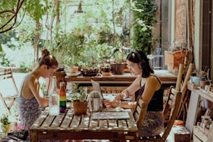 two women are sitting at a table outside