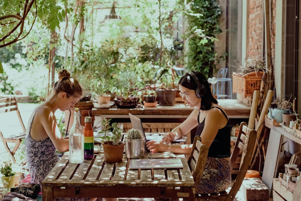 two women are sitting at a table outside