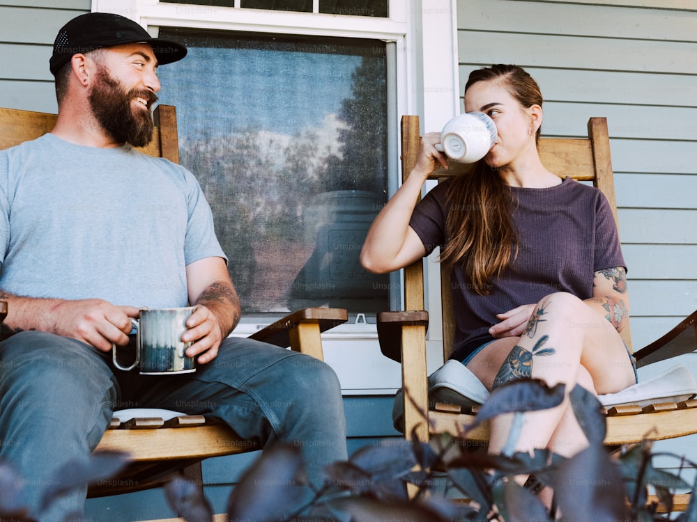 um homem e uma mulher sentados em cadeiras de balanço bebendo café