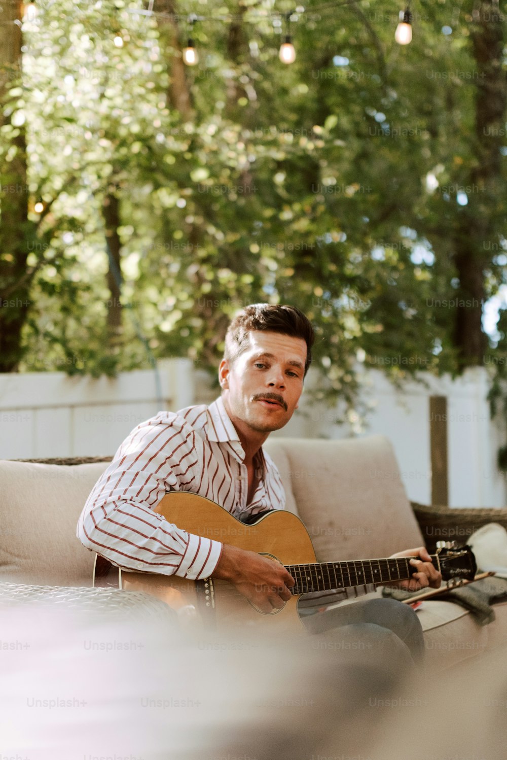 Ein Mann, der auf einer Couch sitzt und Gitarre spielt