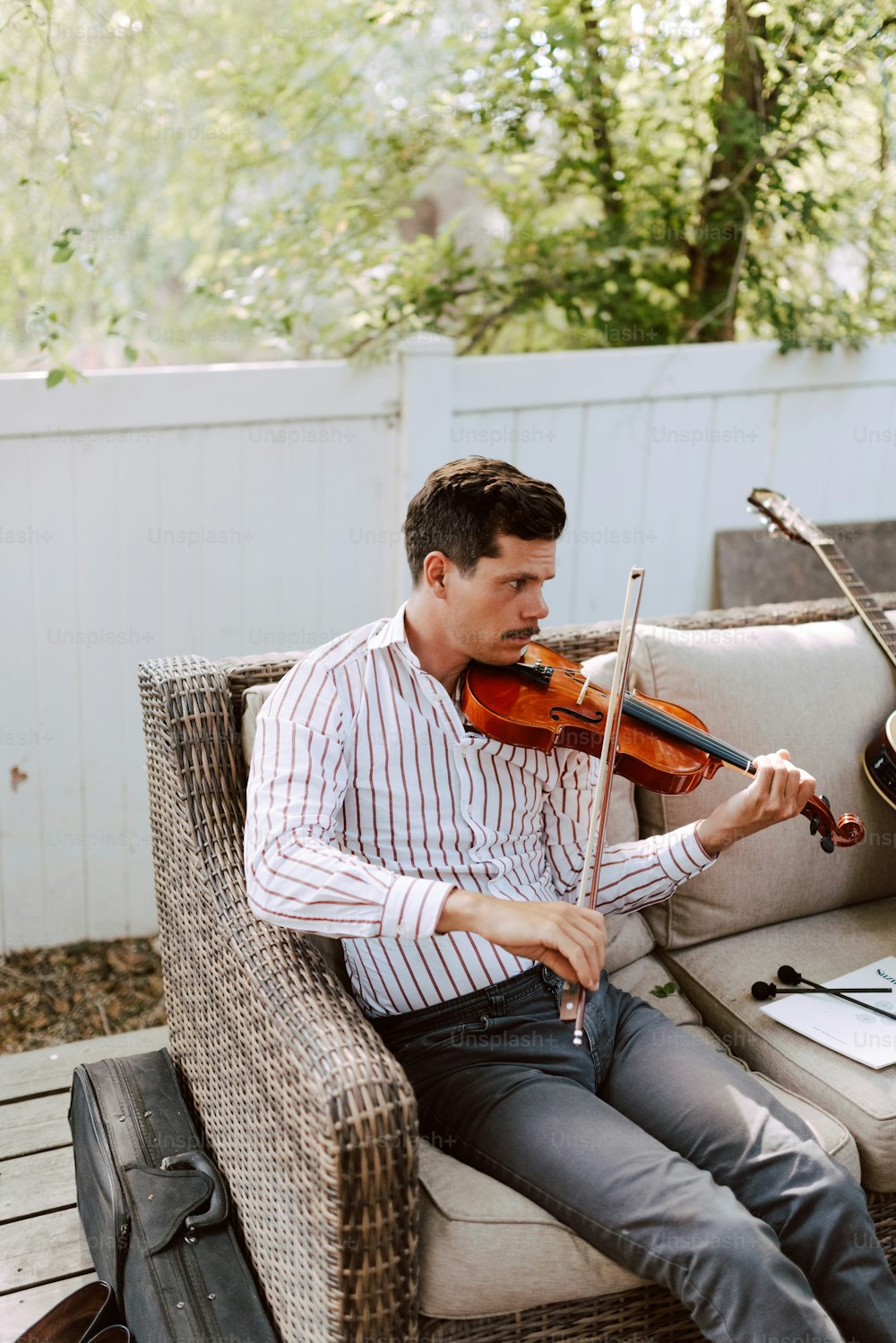 Un hombre sentado en un sofá tocando un violín