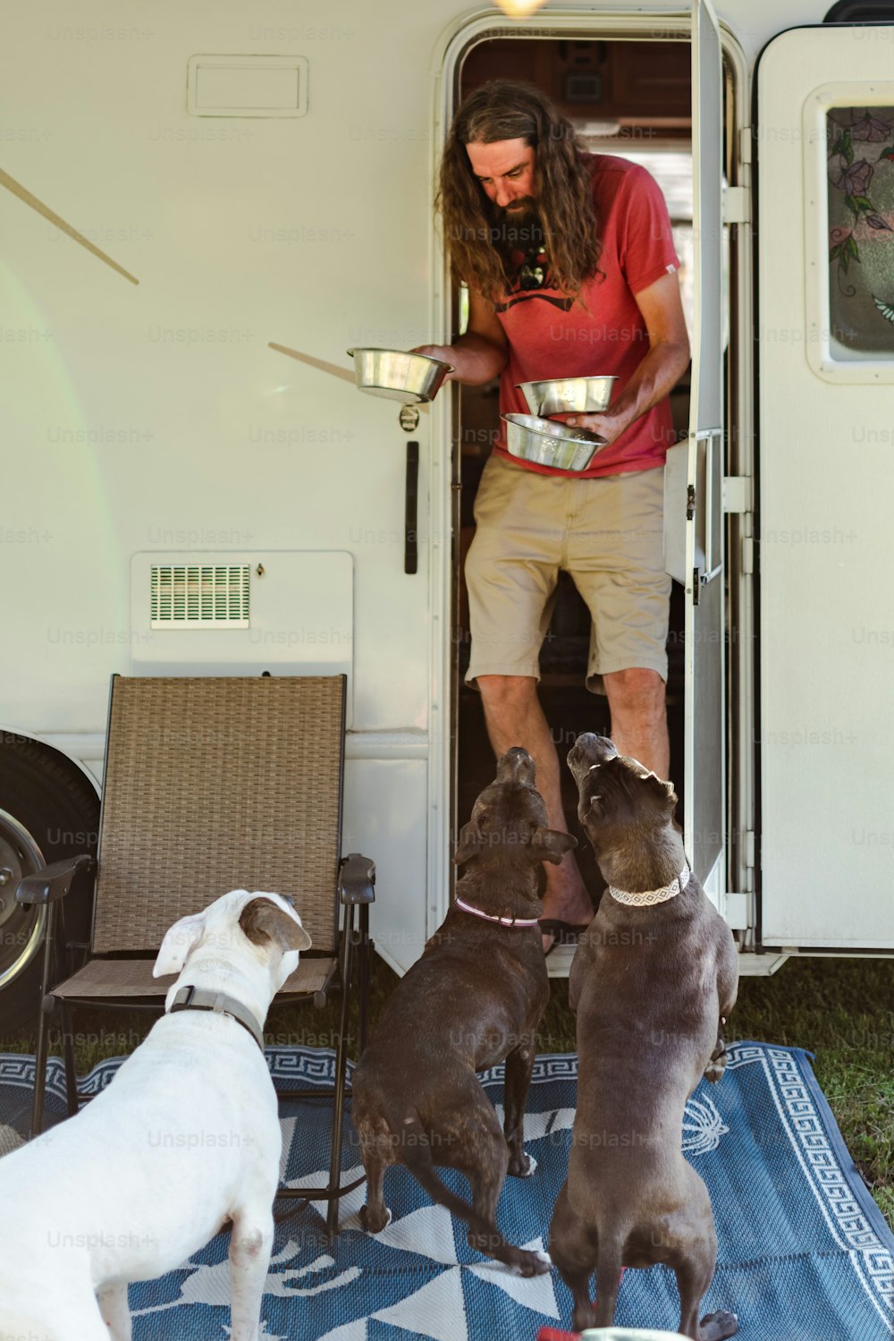 a man standing in the doorway of a trailer with three dogs