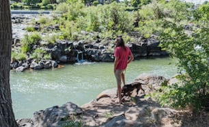 Eine Frau, die auf einem Felsen neben einem Fluss steht