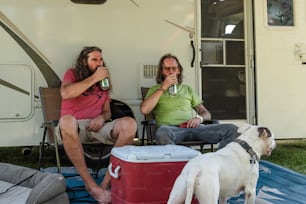 a couple of men sitting on top of a blanket next to a dog