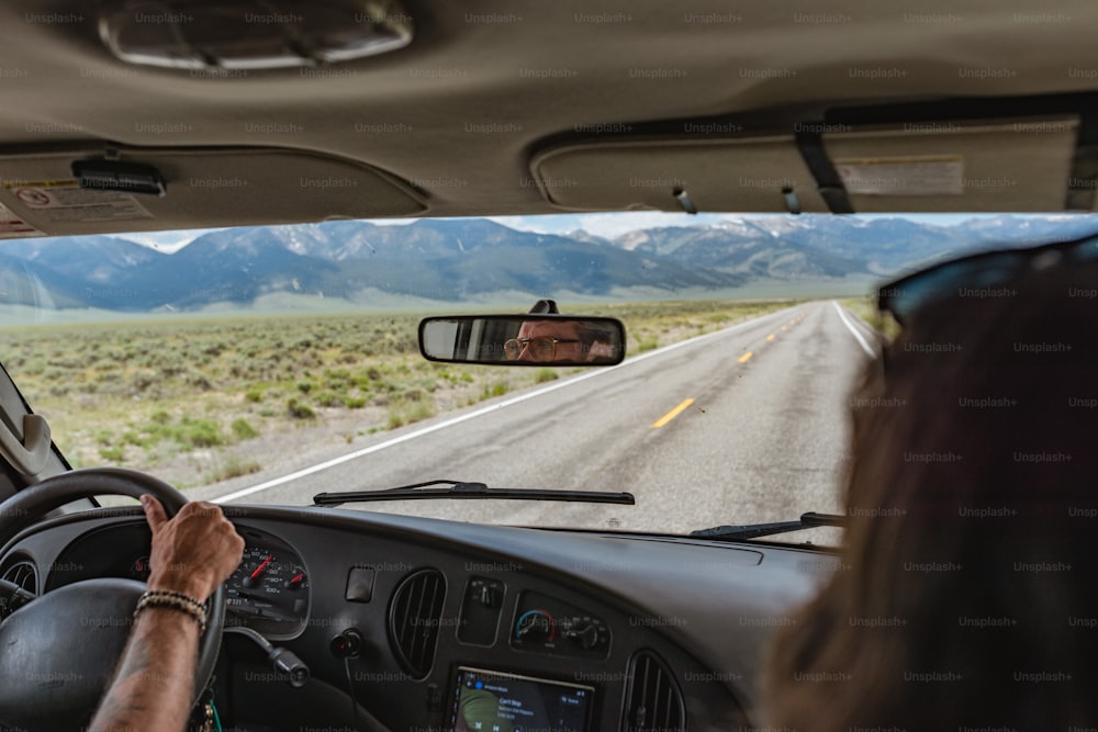 Une femme conduisant une voiture sur une route avec des montagnes en arrière-plan