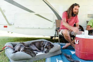 a man sitting next to a dog on a blanket