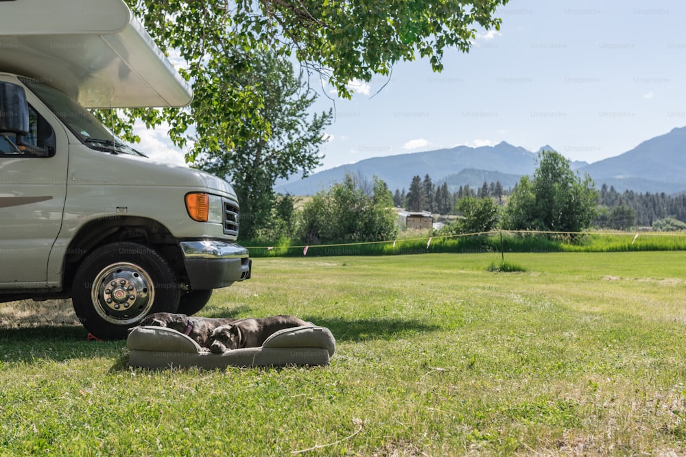 a couple of people laying on the ground in front of a camper