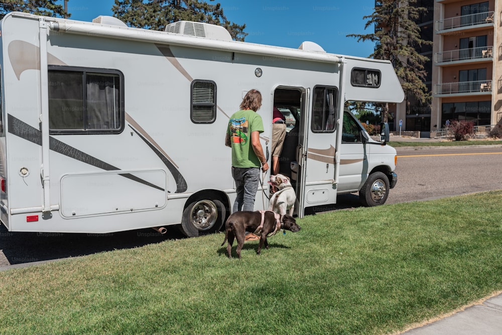 a man and two dogs standing in front of a motor home