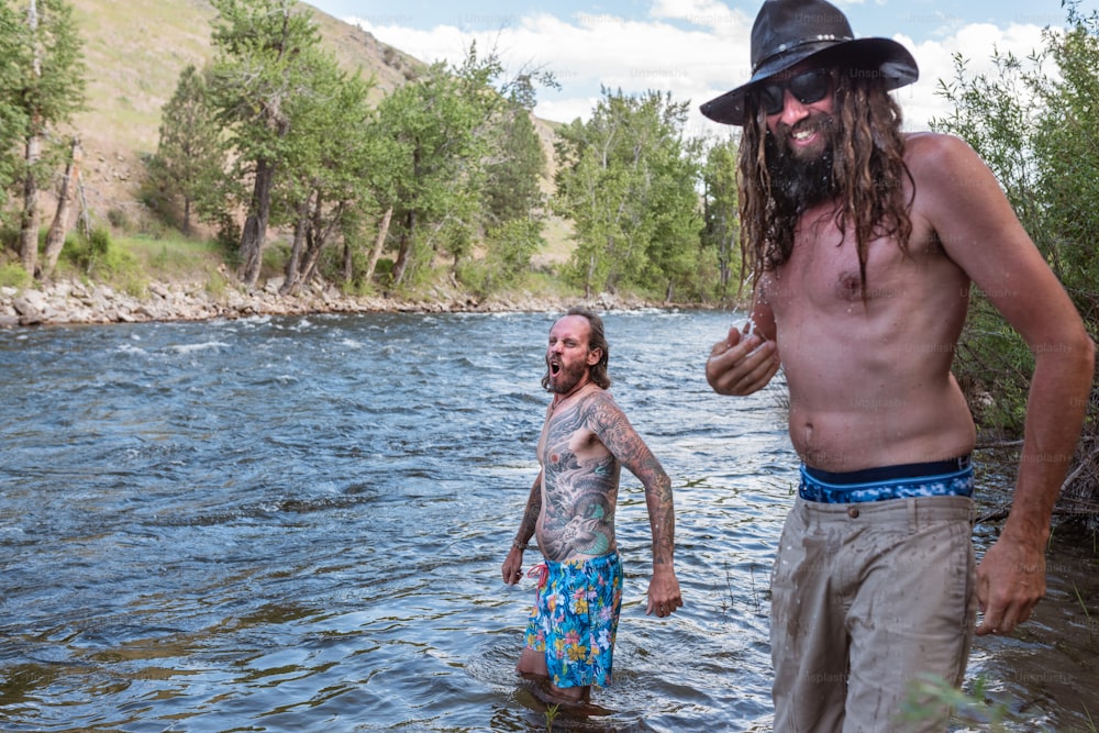 a man with a long beard standing in a river next to another man