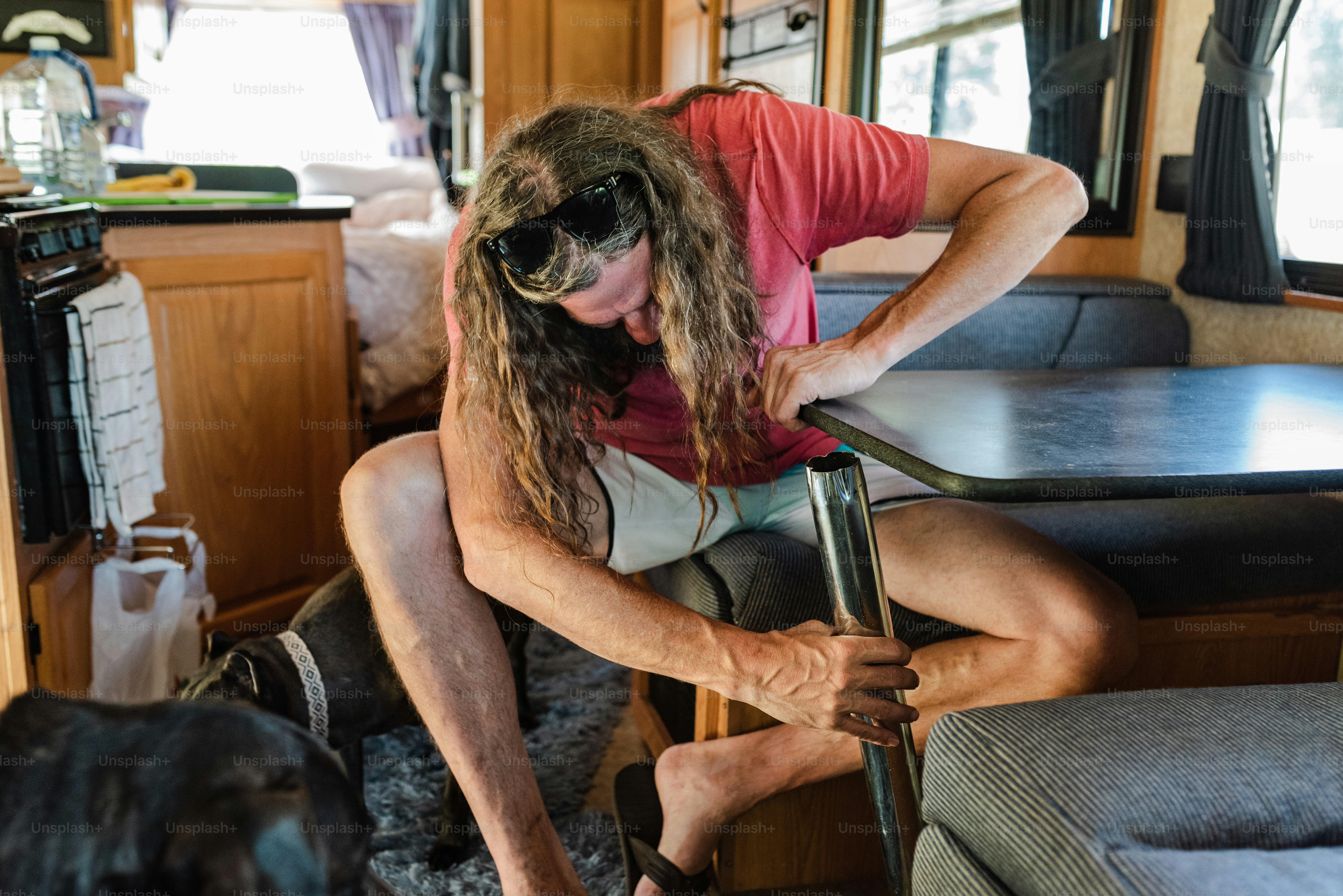 Un uomo con i capelli lunghi seduto su una sedia accanto a un tavolo