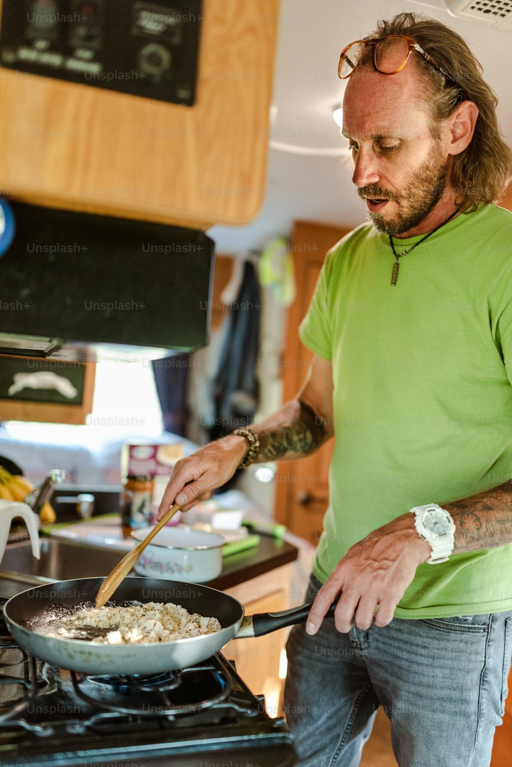 초록색 셔츠를 입은 남자가 난로에서 음식을 요리하고 있다