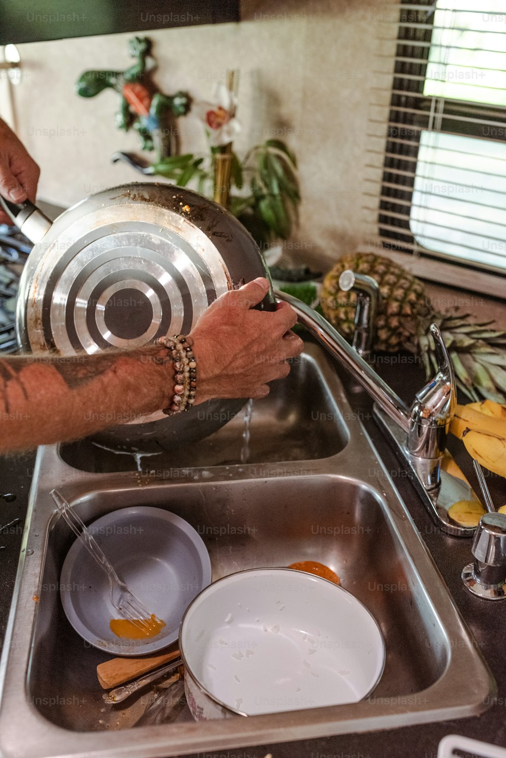 Un homme lave la vaisselle dans un évier de cuisine