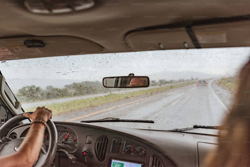 um homem dirigindo um carro por uma estrada encharcada de chuva