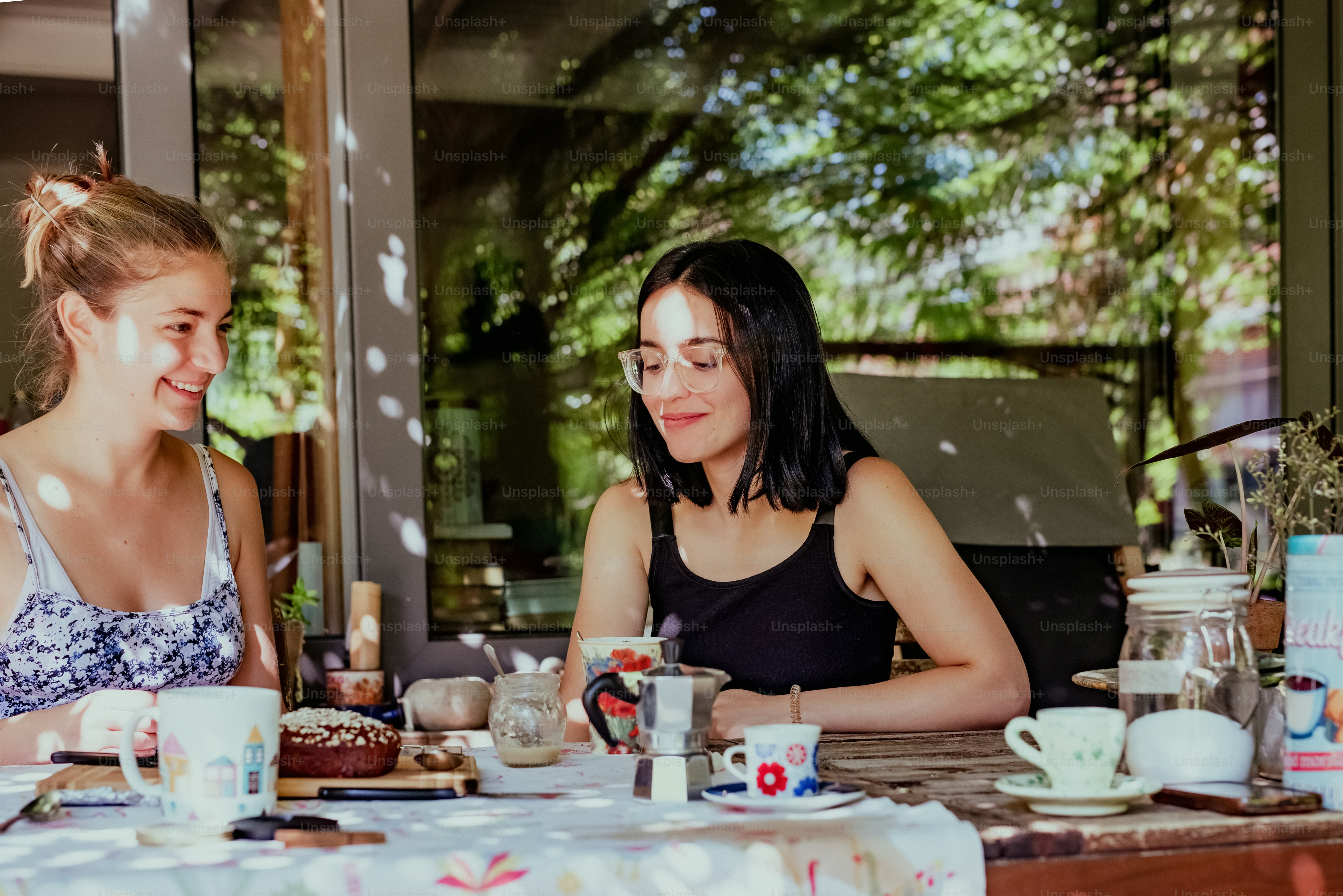 a couple of women sitting at a table with cups