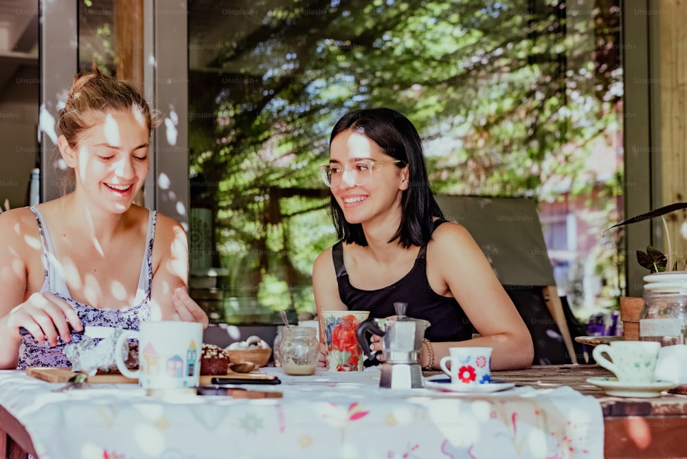 um casal de mulheres sentadas em uma mesa com copos