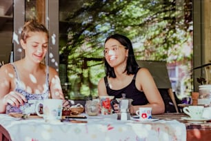 컵이 있는 테이블에 앉아 있는 두 명의 여성