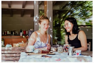 a couple of women sitting at a table with cups