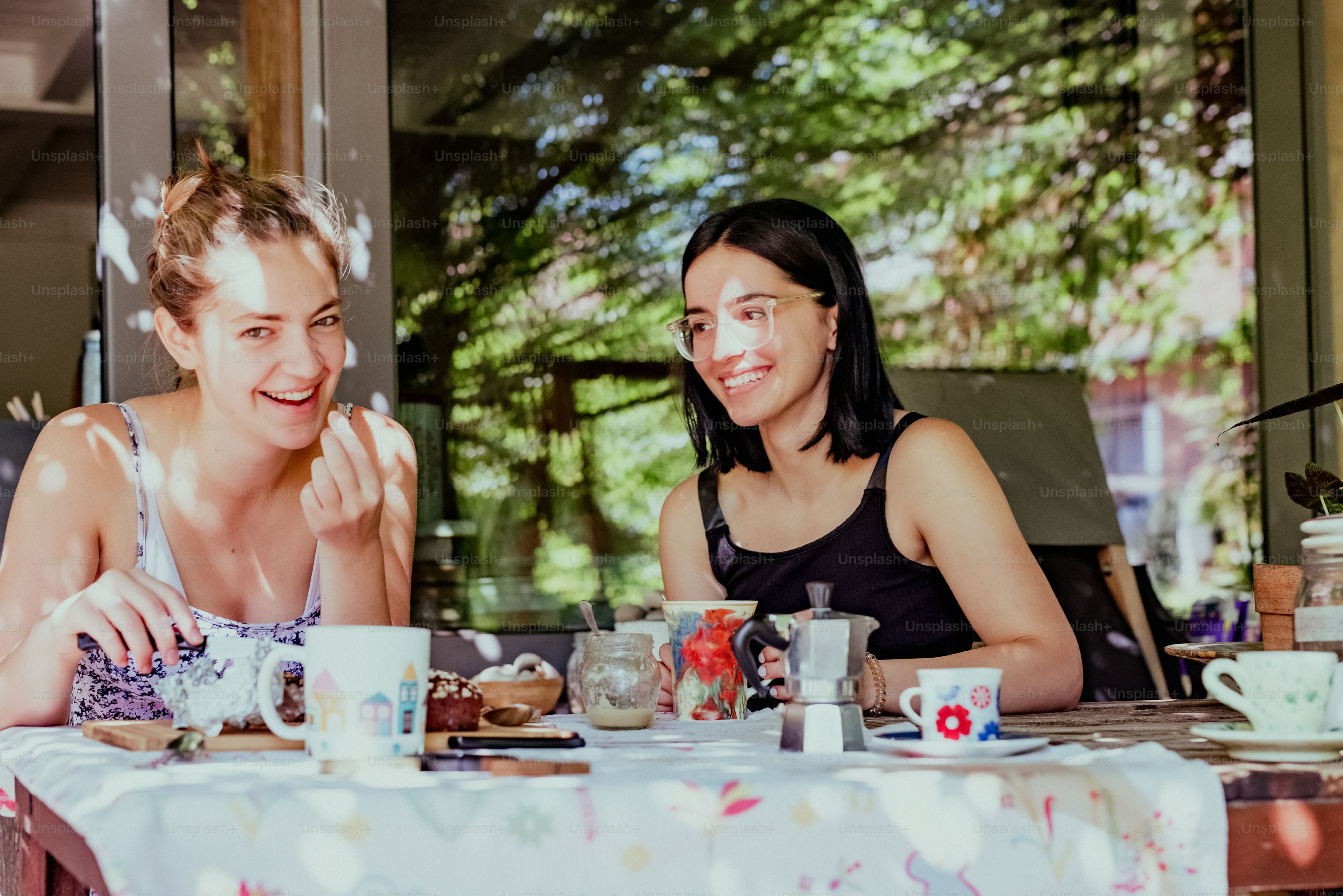 a couple of women sitting at a table with cups